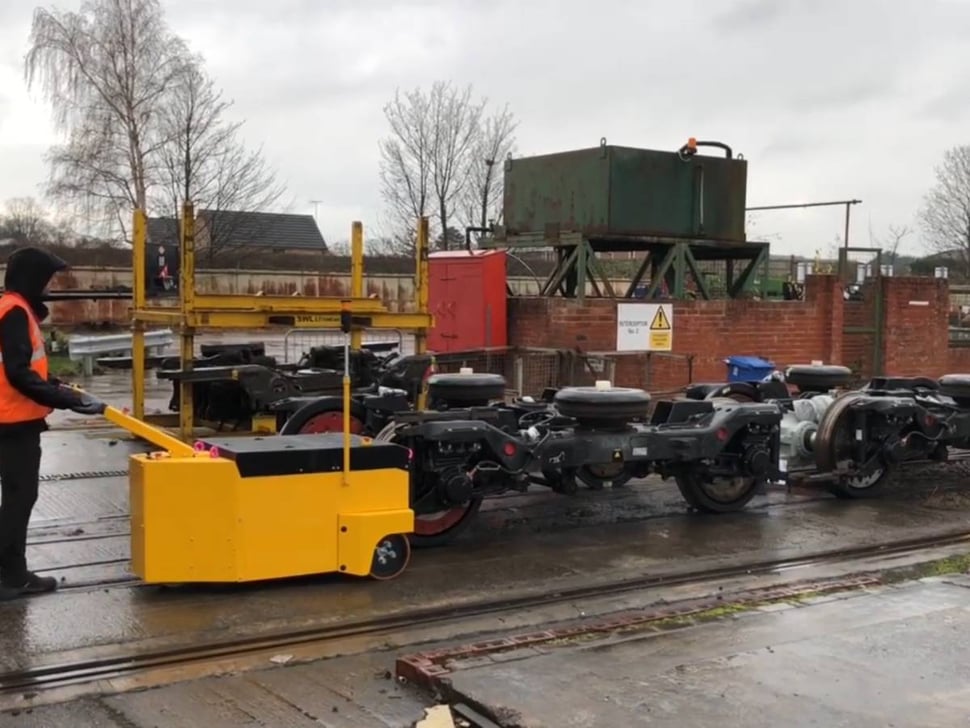 Tracteur pousseur déplaçant des bogies à l'extérieur sous la pluie