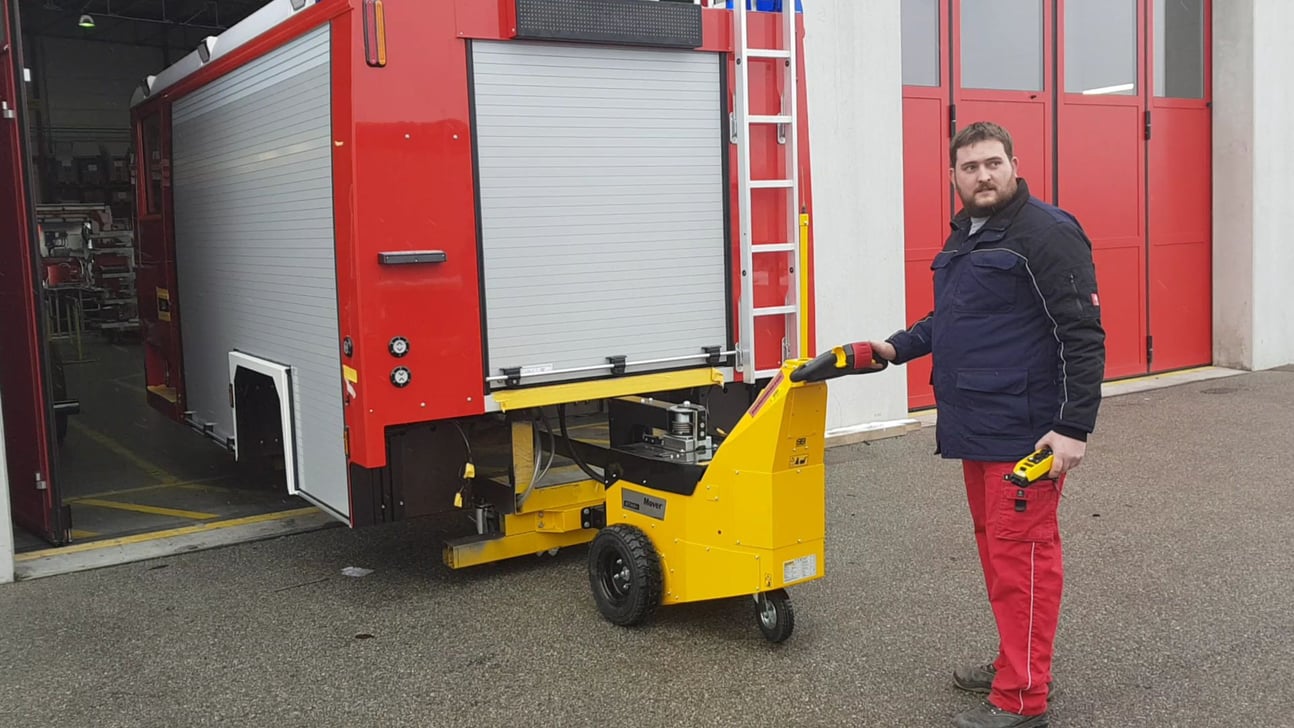 Electric tug moving fire truck in manufacturing
