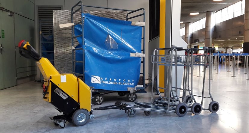 Tracteur pousseur SM100+ déplaçant des chariots à bagages à l'aéroport de Blagnac
