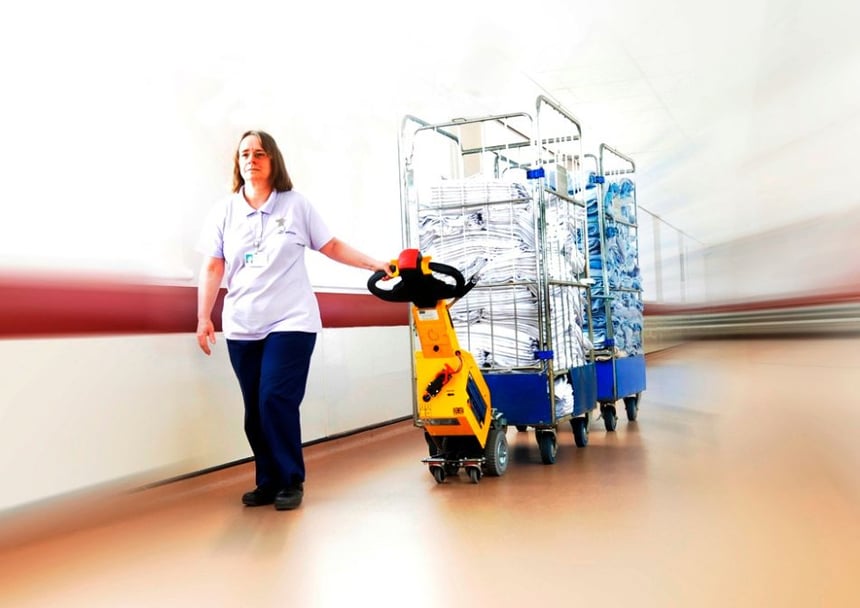 SmartMover SM100+ electric tug moving laundry roll cages in a hospital