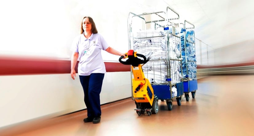 SmartMover SM100+ moving laundry roll cages in a hospital corridor