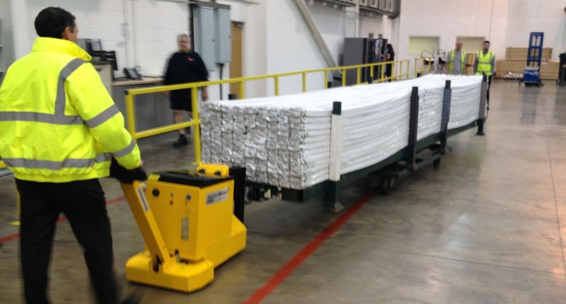 MasterTug déplaçant du plastique transformé sur un chariot dans un entrepôt